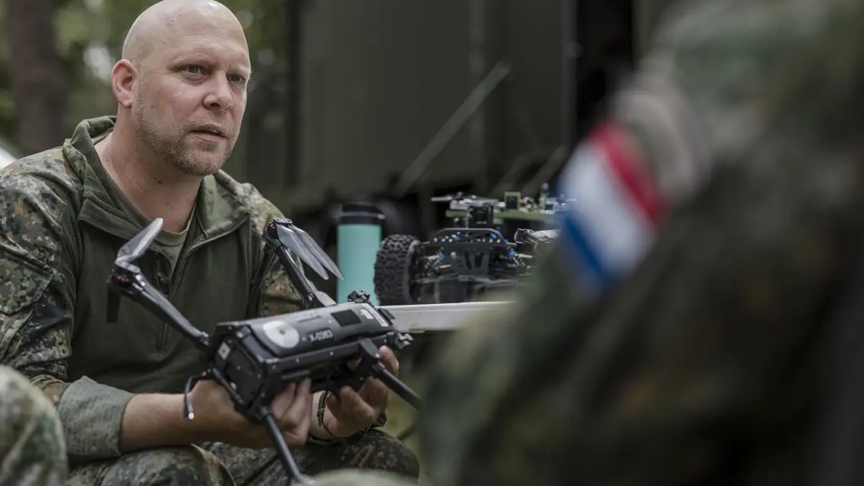 Kapitein Max van TechDevOps demonstreert tijdens oefening Fighter Lion een onbemand systeem aan collega-militairen.