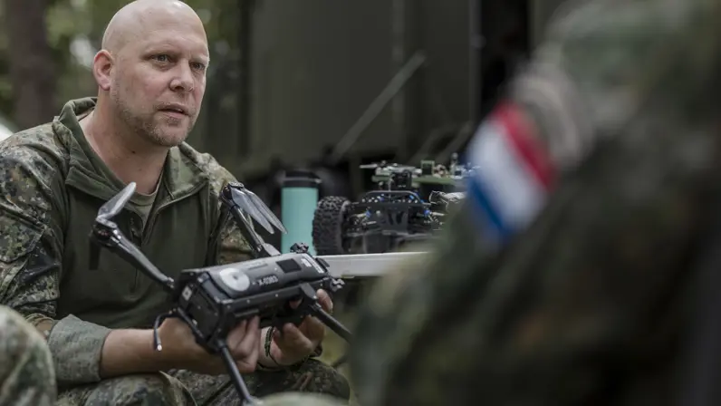 Kapitein Max van TechDevOps demonstreert tijdens oefening Fighter Lion een onbemand systeem aan collega-militairen.