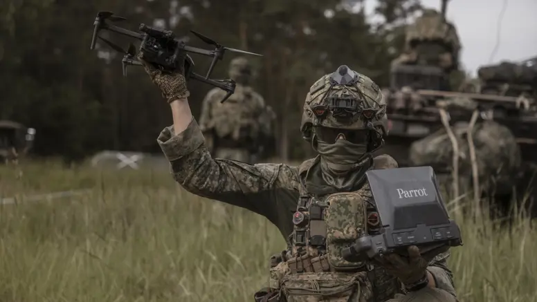 Een militair tijdens oefening Fighter Lion houdt een Parrot-verkenningsdrone omhoog terwijl hij de controller vasthoudt.