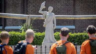 Studenten staan bij het monument te kijken