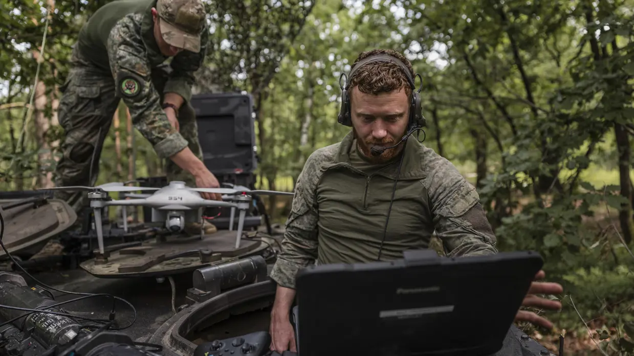 Eerste luitenant Jim werkt met een laptop terwijl korporaal Dylan een verkenningsdrone gereedmaakt voor een test van het AITAS-systeem tijdens oefening Fighter Lion.