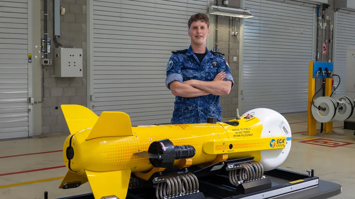 Een militair poseert achter een aquatische drone.