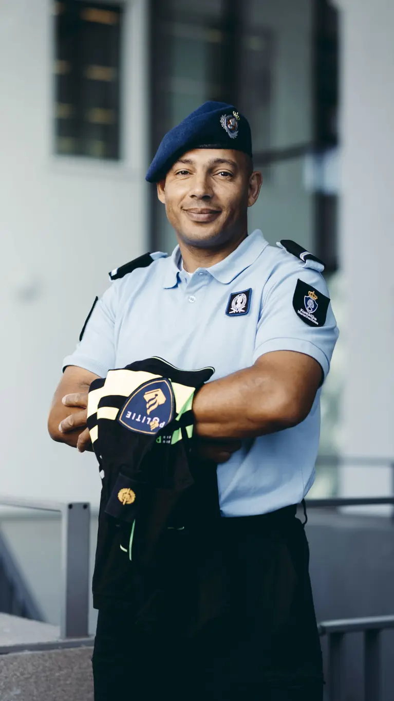 Wachtmeester Lesley in uniform, met een politieshirt over z’n armen.