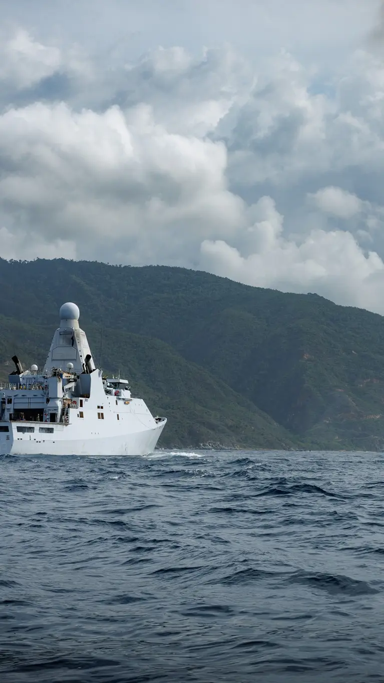 Een marinecollega kijkt hoe in de verte een helikopter een vracht oppakt van een marineschip.