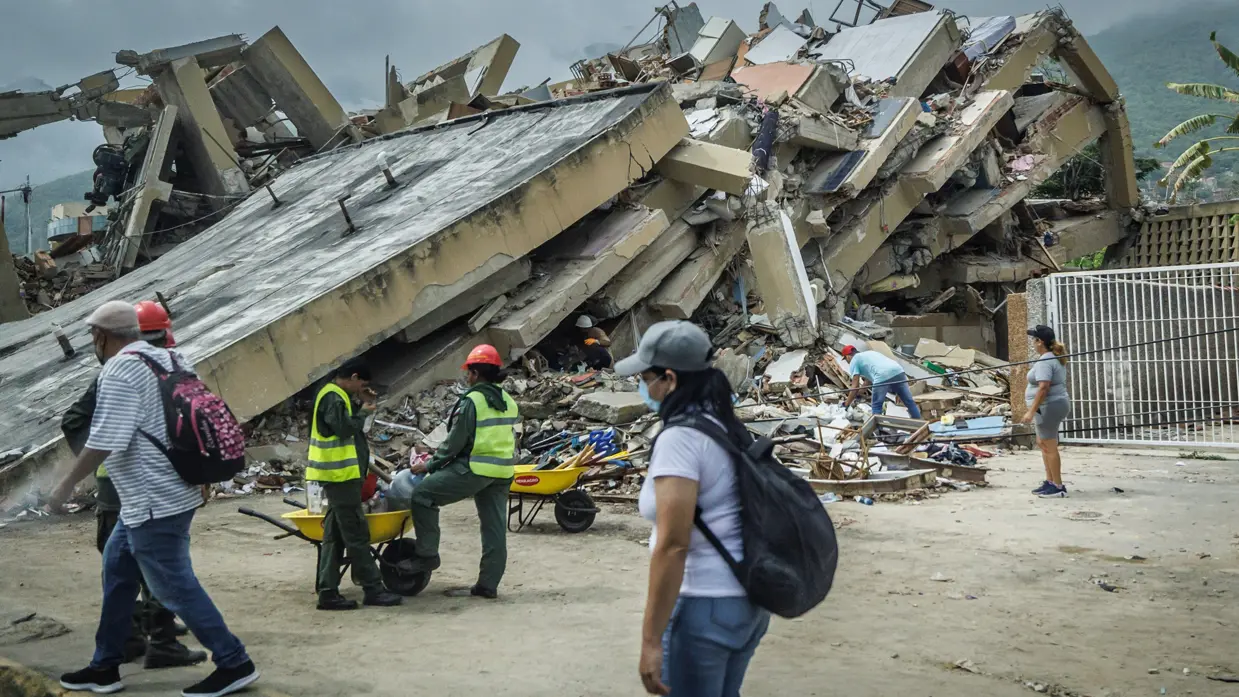 Er lopen mensen langs een volledig ingestort gebouw. 