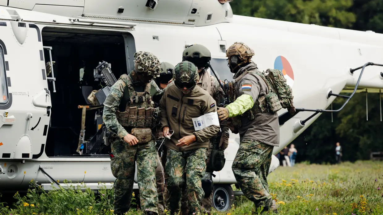 Een groep militairen stapt uit bij een helikopter.