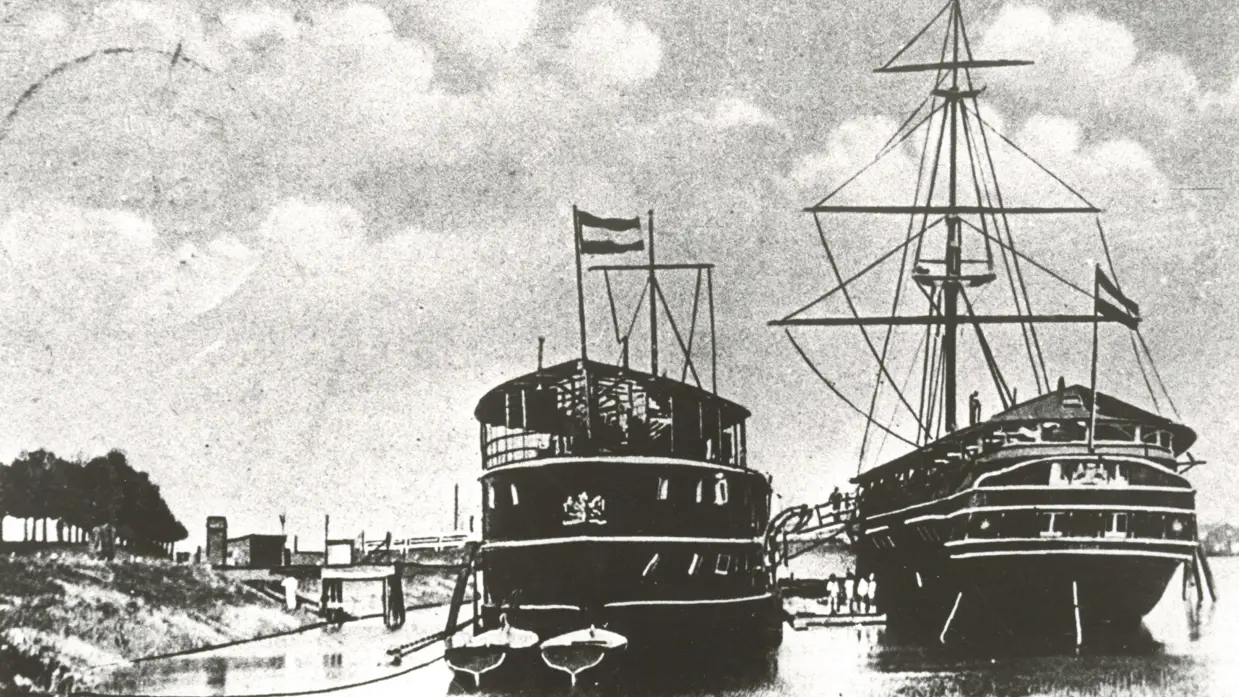 2 historische schepen, een stoomschip en een zeilschip, afgemeerd in een haven bij Gorinchem, met vlaggen en mensen aan boord.