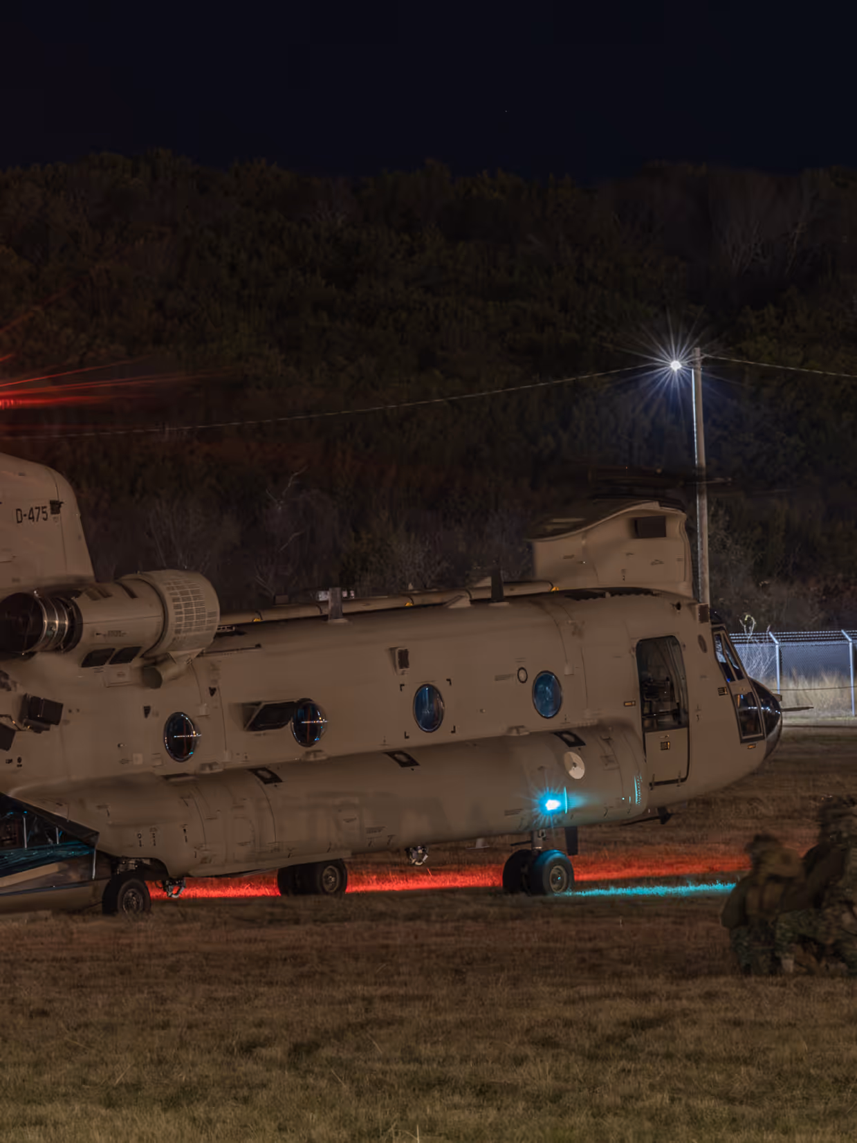 Nachtopname van een Chinook op de grond met luchtmobiele infanteristen er omheen.