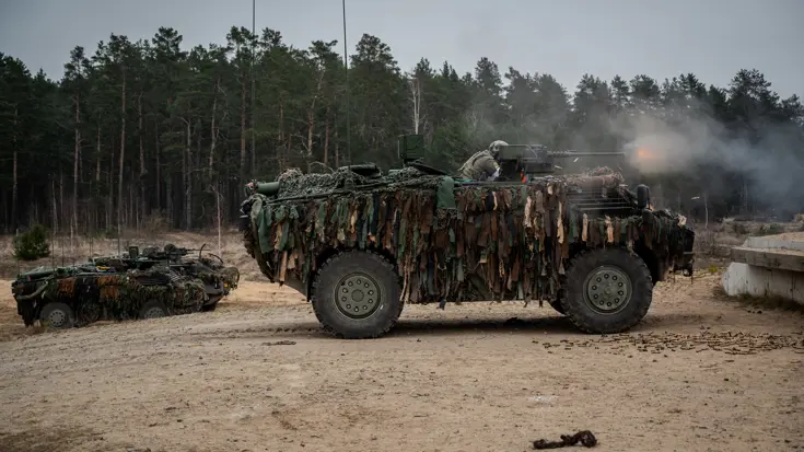 Militairen schieten vanuit een Fennek-voertuig.