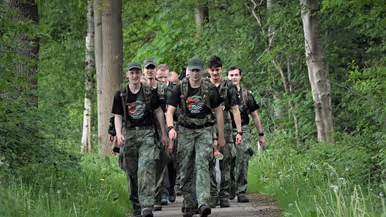 De militairen lopen door een bosgebied.