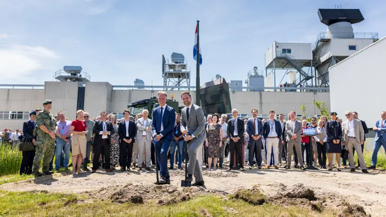 Twee mannen steken een schop in de grond. 