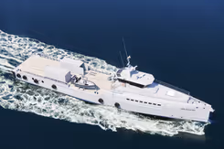 Wit patrouilleschip vaart met snelheid op donkerblauw water.