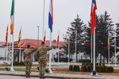 2 Nederlandse militairen salueren voor een rij vlaggen.