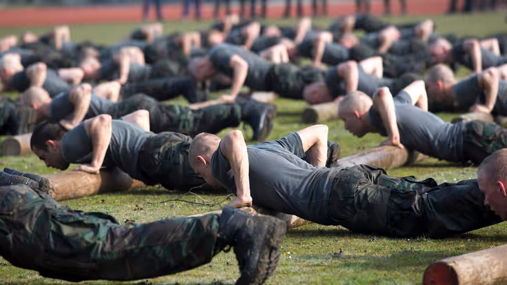 Groep militairen is aan het opdrukken in het gras.