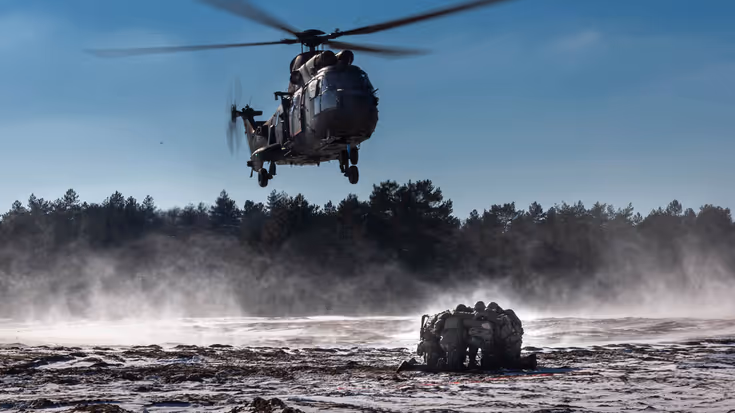 Een helikopter hangt boven een groep militairen.