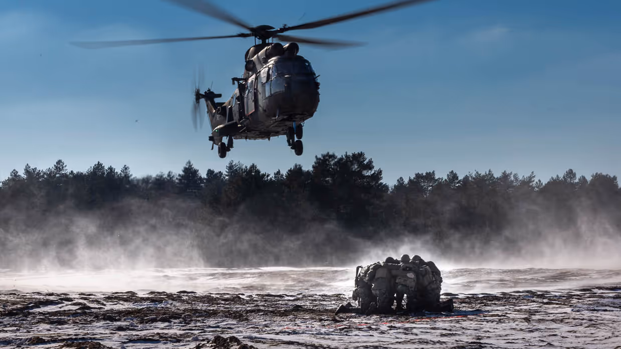 Een helikopter hangt boven een groep militairen.