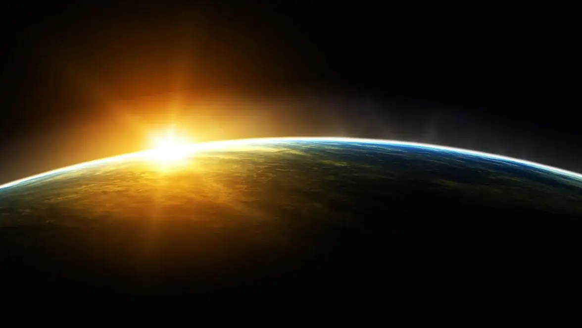 Deel van de aarde vanaf de ruimte gezien, waarbij de zon deels achter de horizon schuilgaat.