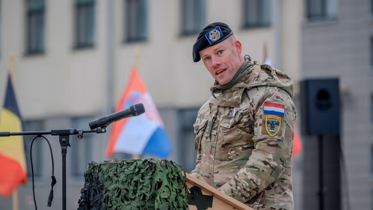 Militair in uniform houdt toespraak vanachter katheder.