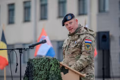 Militair in uniform houdt toespraak achter katheder.