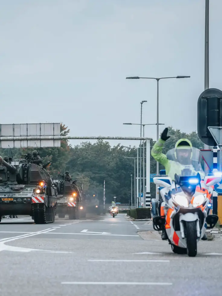 Een motor van de Marechaussee met op de achtergrond voertuigen van de Landmacht.