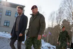 Staatssecretaris Derk Boswijk loopt naast een militair. Op de grond ligt sneeuw.
