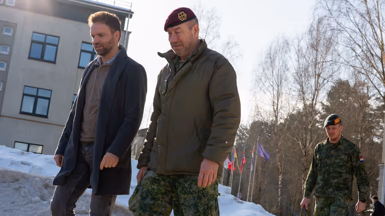 Staatssecretaris Derk Boswijk loopt naast een militair. Op de grond ligt sneeuw.