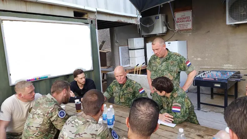 Militairen zitten aan een tafel en zijn met elkaar in gesprek.