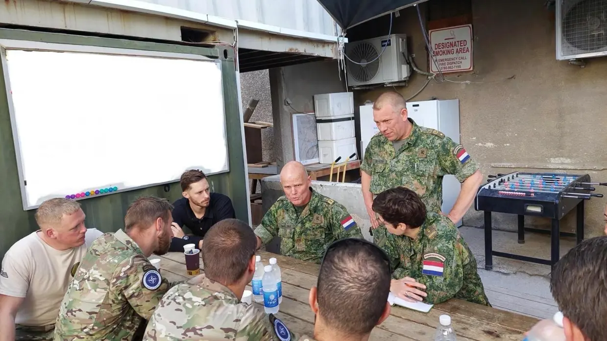 Militairen zitten aan een tafel en zijn met elkaar in gesprek.