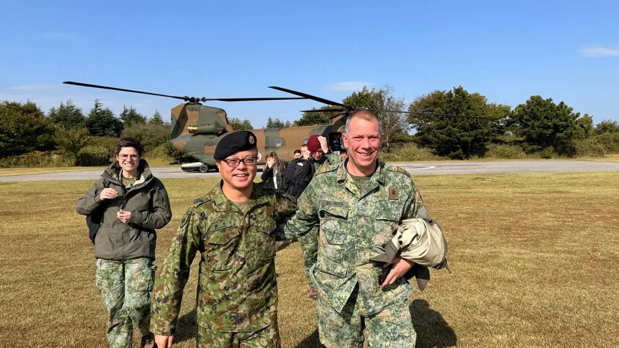 Twee militairen op de foto. Op de achtergrond een helikopter.