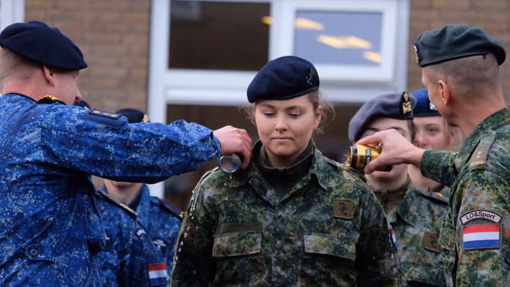 De prinses krijgt ter afronding van haar militaire opleiding bier over haar schouders gegoten.