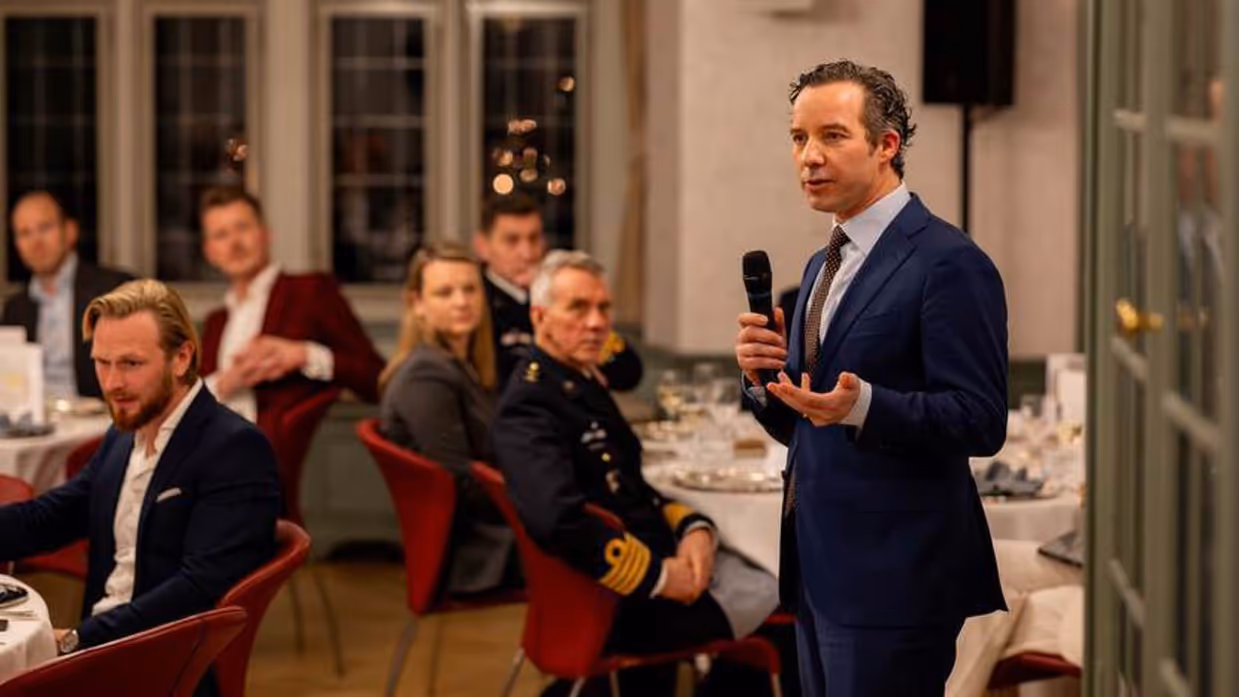 Een hoogleraar spreekt een zaal toe.