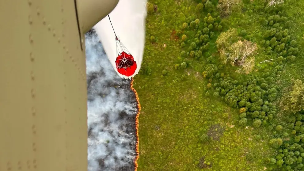 Een helikopter dropt water op een natuurbrand.