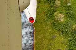 Een helikopter dropt water op een natuurbrand.