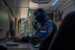 Onherkenbare militair zit achter een computer.