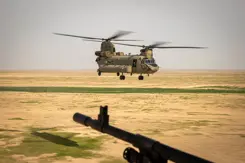 Chinook-transporthelikopter vlak boven de grond in woestijngebied. 