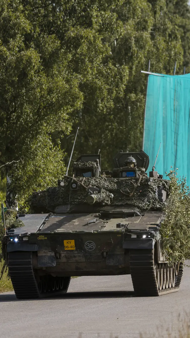 Militaire voertuigen rijden achter elkaar over de weg.