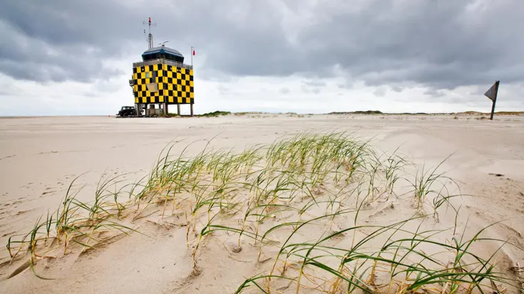  Een geelzwart geblokt huisje op het strand.