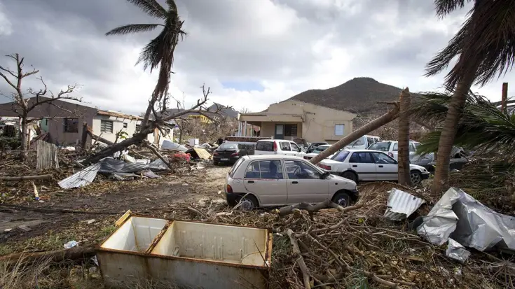 Een woonwijk na de verwoestende passage van orkaan Irma, met zwaar beschadigde huizen, auto’s en omgevallen palmbomen.