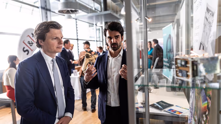 De minister luistert naar een toelichting van een bedrijf.