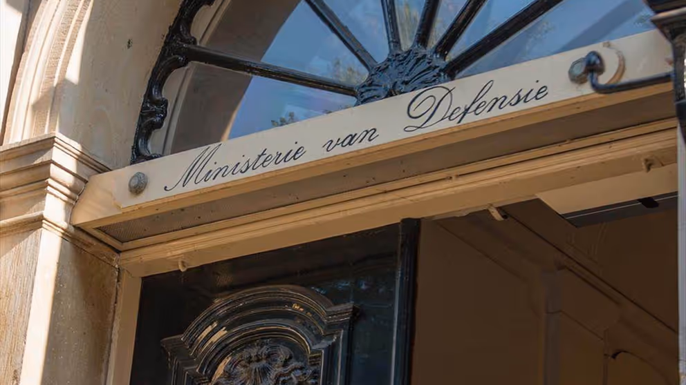 Bovenzijde van historische deur met de tekst Ministerie van Defensie op de deurstijl.