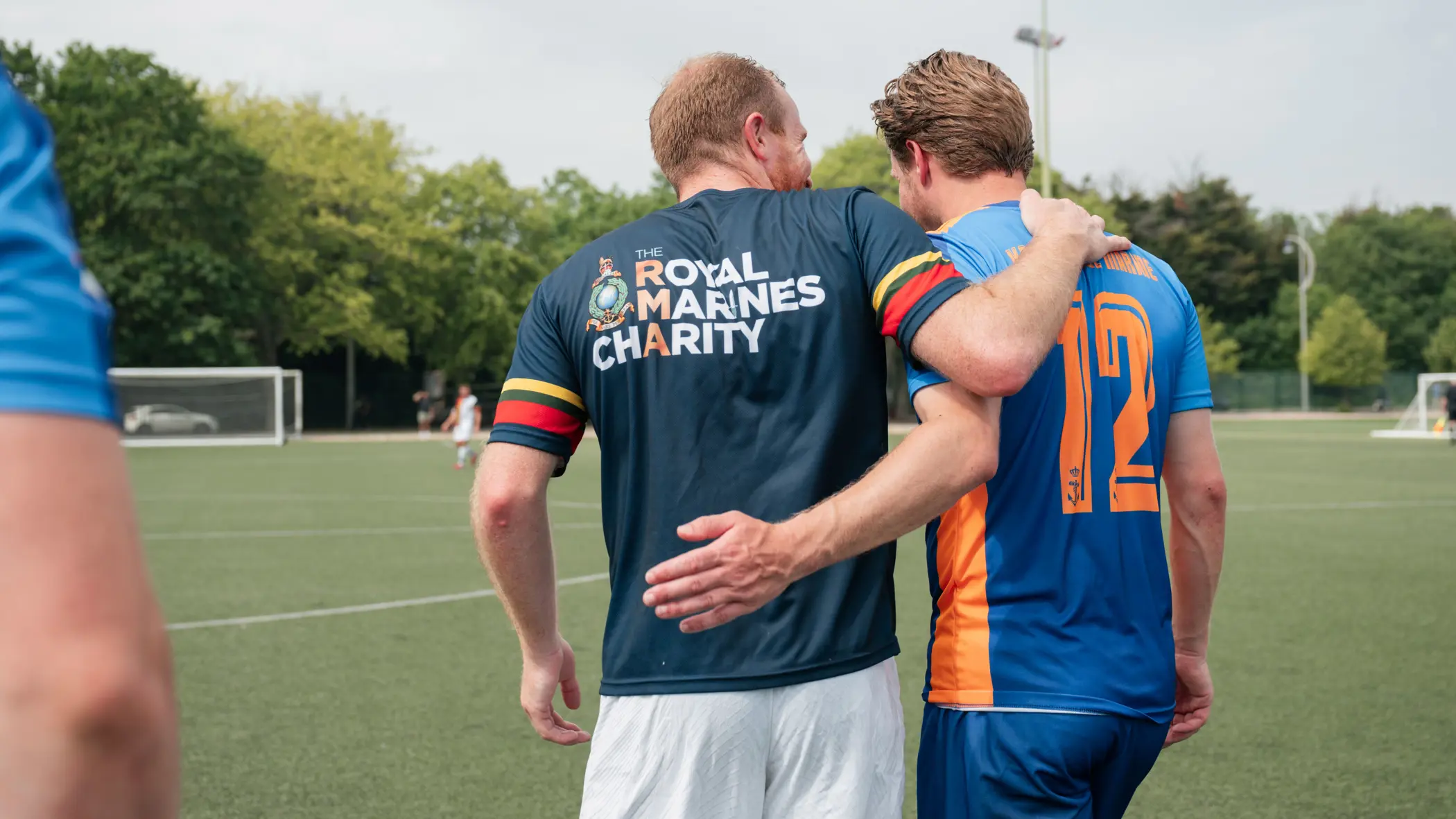 Nederlandse en Engelse mariniers lopen gearmd op het voetbalveld.