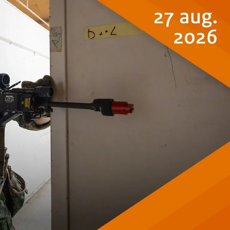 Een militair loopt een deur door met een geweer.