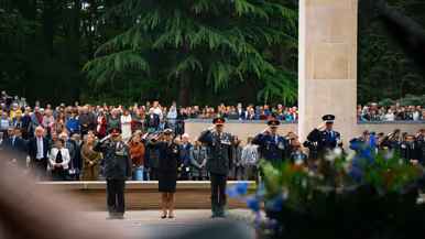 Vijf militairen van land- en luchtmacht, marine en marechaussee brengen de eregroet voor het monument. Achter hen staan lange rijen publiek.