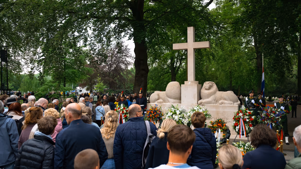  Militairen staan in de houding   Mensen lopen langs het monument 