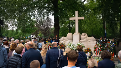Publiek voor het Nationaal Monument op de Grebbeberg, waarvoor kransen staan en liggen. 