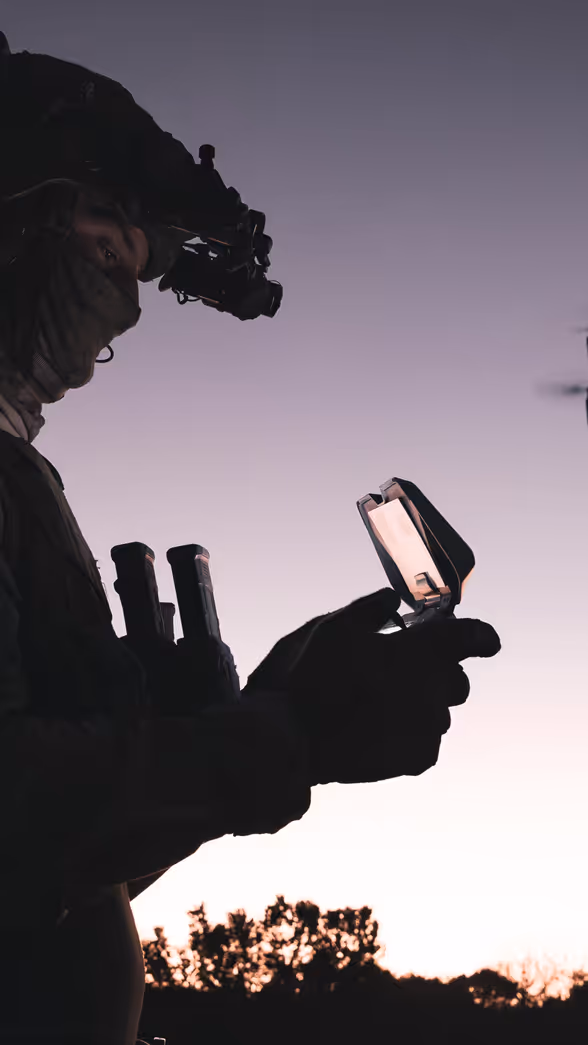 Militair bestuurt drone bij zonsondergang.