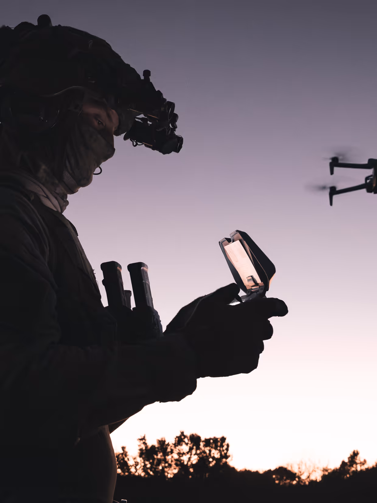 Militair bestuurt drone bij zonsondergang.