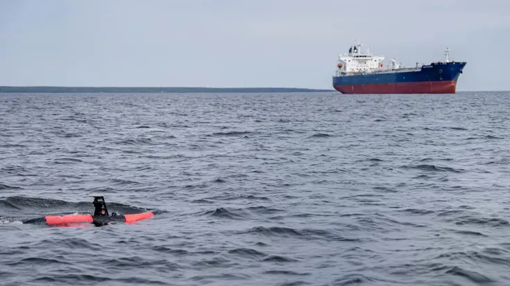 De Scout in zee met een schip op de achtergrond.