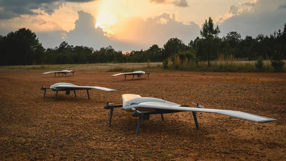 Vier drones staan op open veld in bosrijke omgeving.