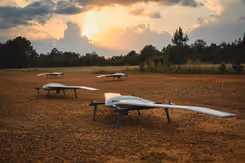 Vier drones staan op open veld in bosrijke omgeving.